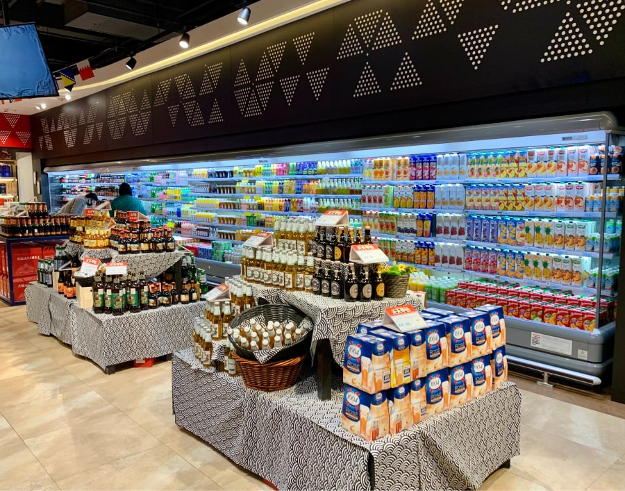 Fotografia da entrada de uma loja de conveniência, com pequenas ilhas para destaque de produtos