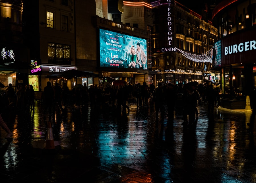 Imagem de praça à noite iluminada com a luz de diversos Displays Digitais