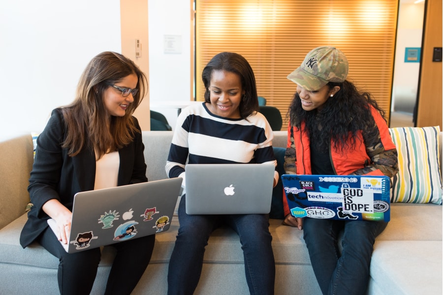 3 jovens de portátil discutem trabalhos em agência de marketing digital