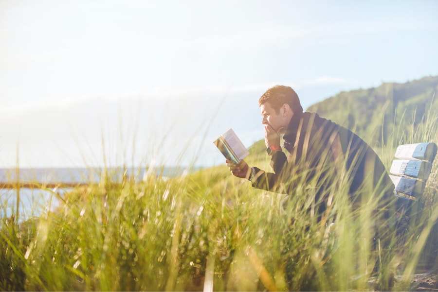 Jovem a ler um livro num banco de jardim  - provavelmente uma das nossas recomendações de livros para marketing digital