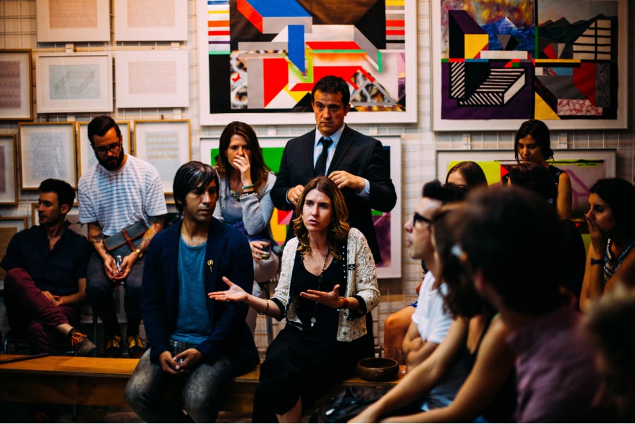 Reunião de grupo de trabalho em empresa. Mulher no centro fala com todo o grupo. Comunicação 360 para a sua empresa.