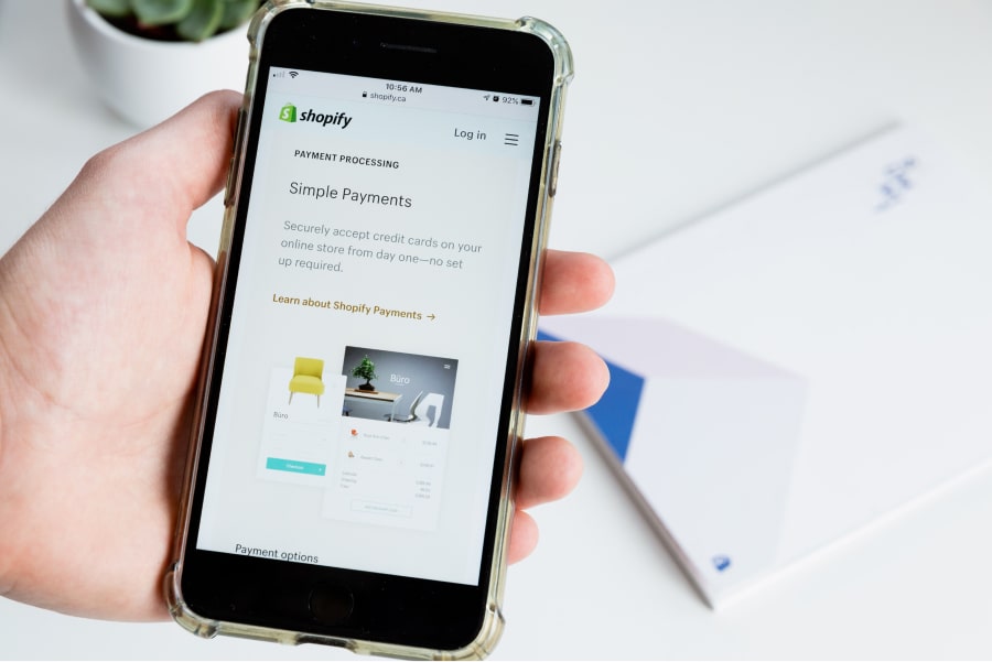 Foto de telemóvel com um website de uma loja online do shopify no ecrã como exemplo de merchandising no ponto de venda