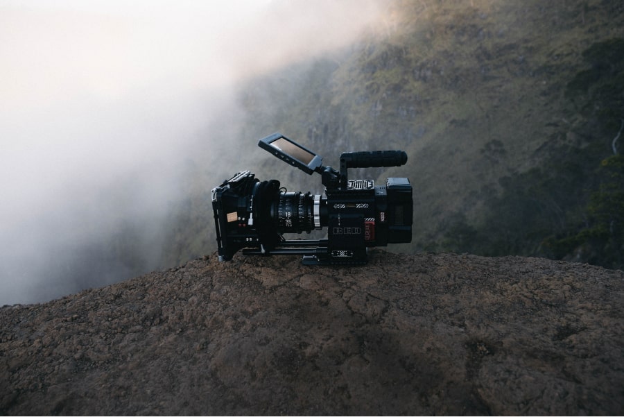 Fotografia de câmara de filmar profissional sobre uma rocha, com uma paisagem de montanha em pano de fundo - 3 apps para legendar videos e produzir conteúdos mais inclusivos