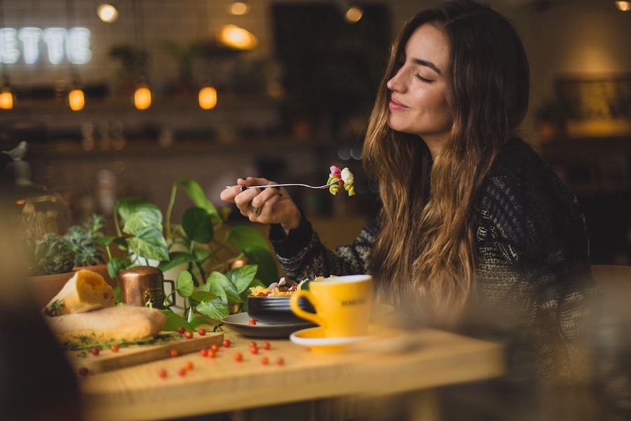 Uma jovem à mesa a saborear uma refeição - Comunicação na restauração: lições pós-pandemia